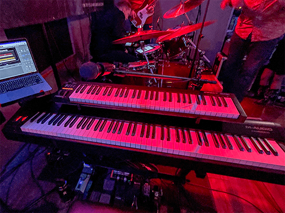 Jon's two-keyboard rig onstage under red lights